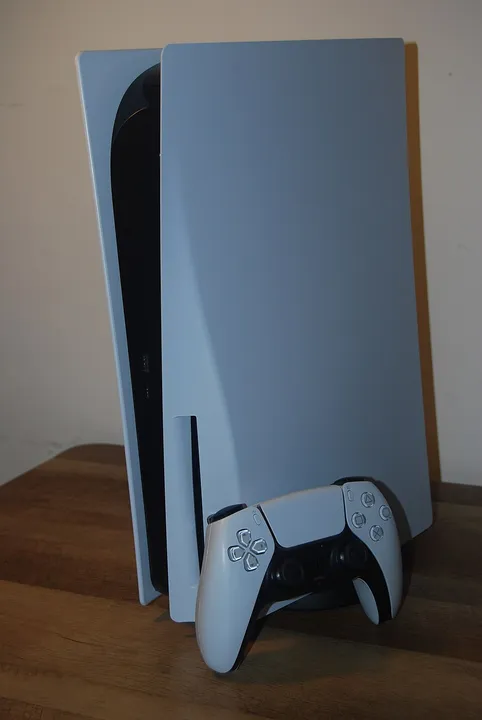 Original disc-equipped PlayStation 5 standing beside a DualSense controller