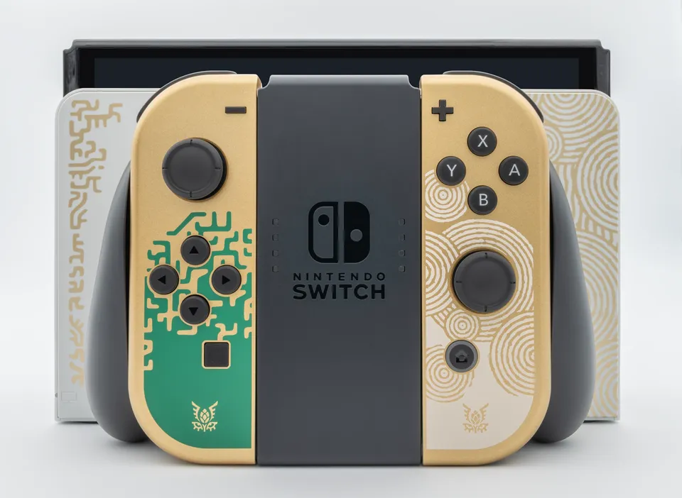 Tears of the Kingdom OLED dock and console behind gold Joy-Con controllers in a grip