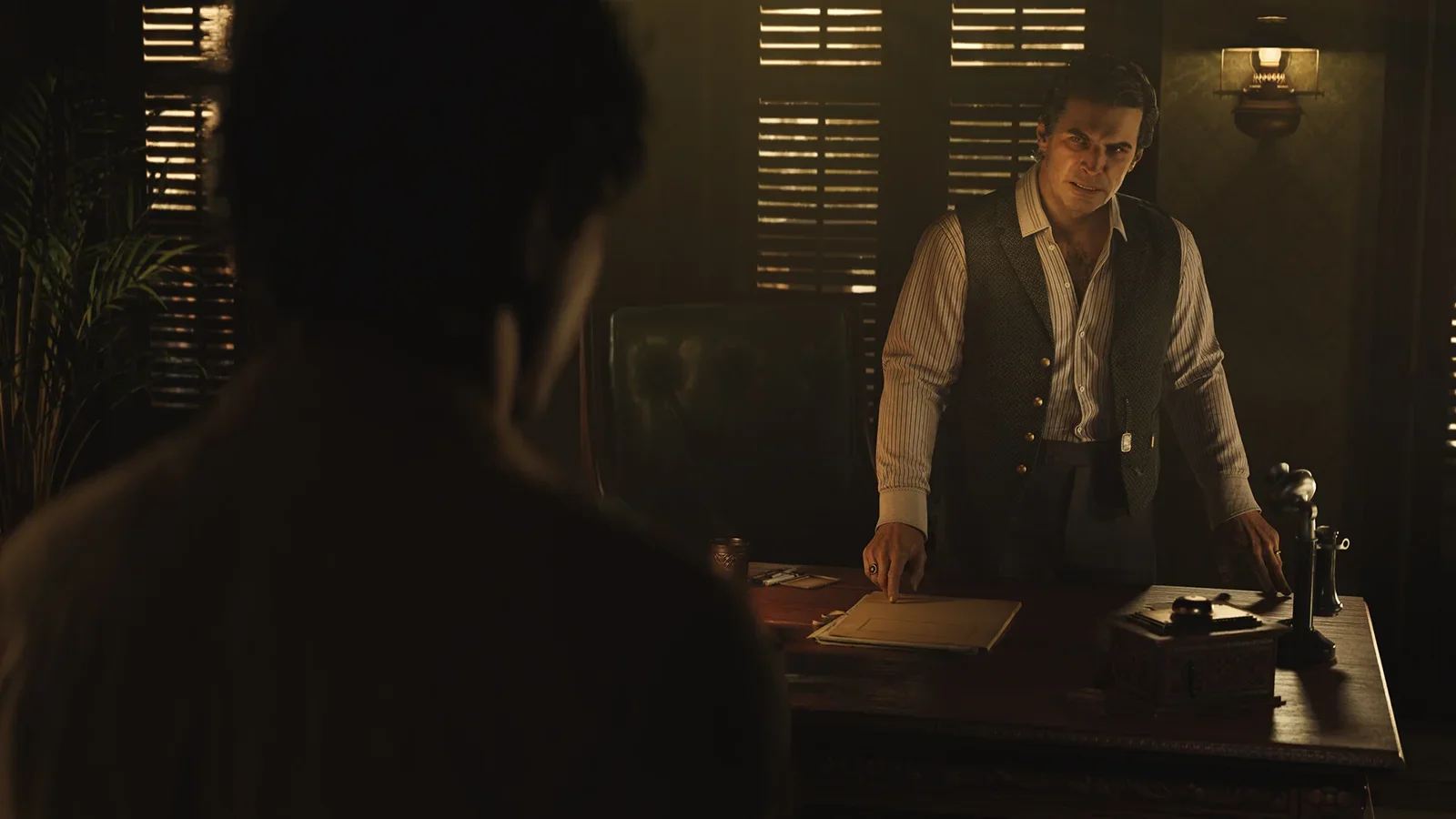 Official Mafia: The Old Country screenshot of a Torrisi family member at a desk in a dim office