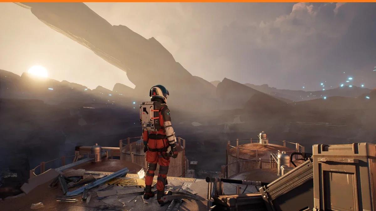 An astronaut in an orange and white spacesuit stands on a wrecked metal platform looking out over a hazy rocky landscape at sunrise