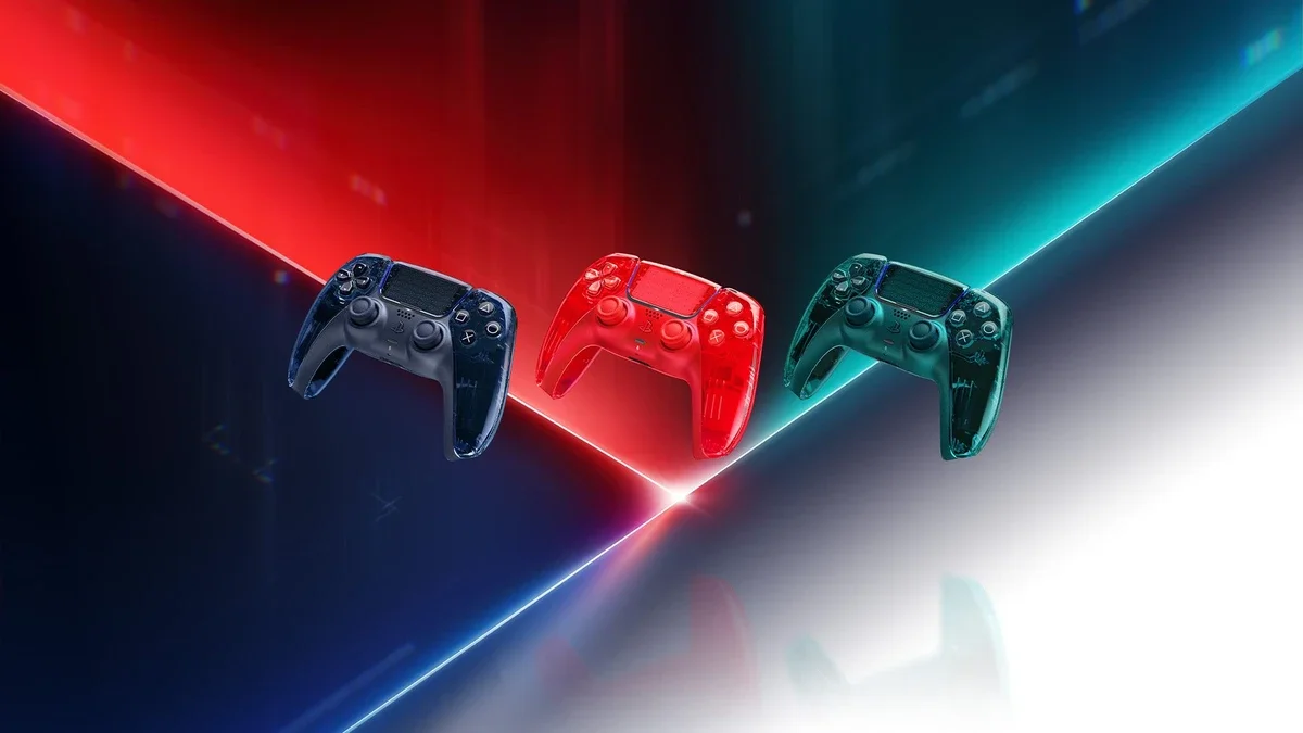 Three transparent DualSense controllers in grey, orange-red and green float above a glossy floor lit by red and teal light beams