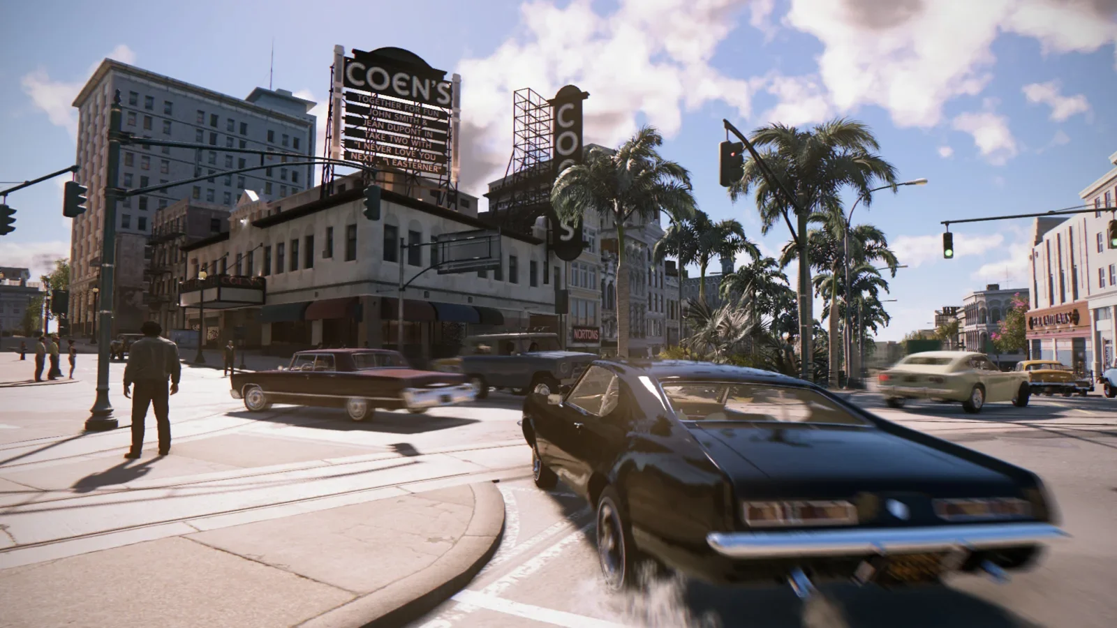 Official Mafia III: Definitive Edition screenshot of a 1960s car on a palm-lined New Bordeaux street