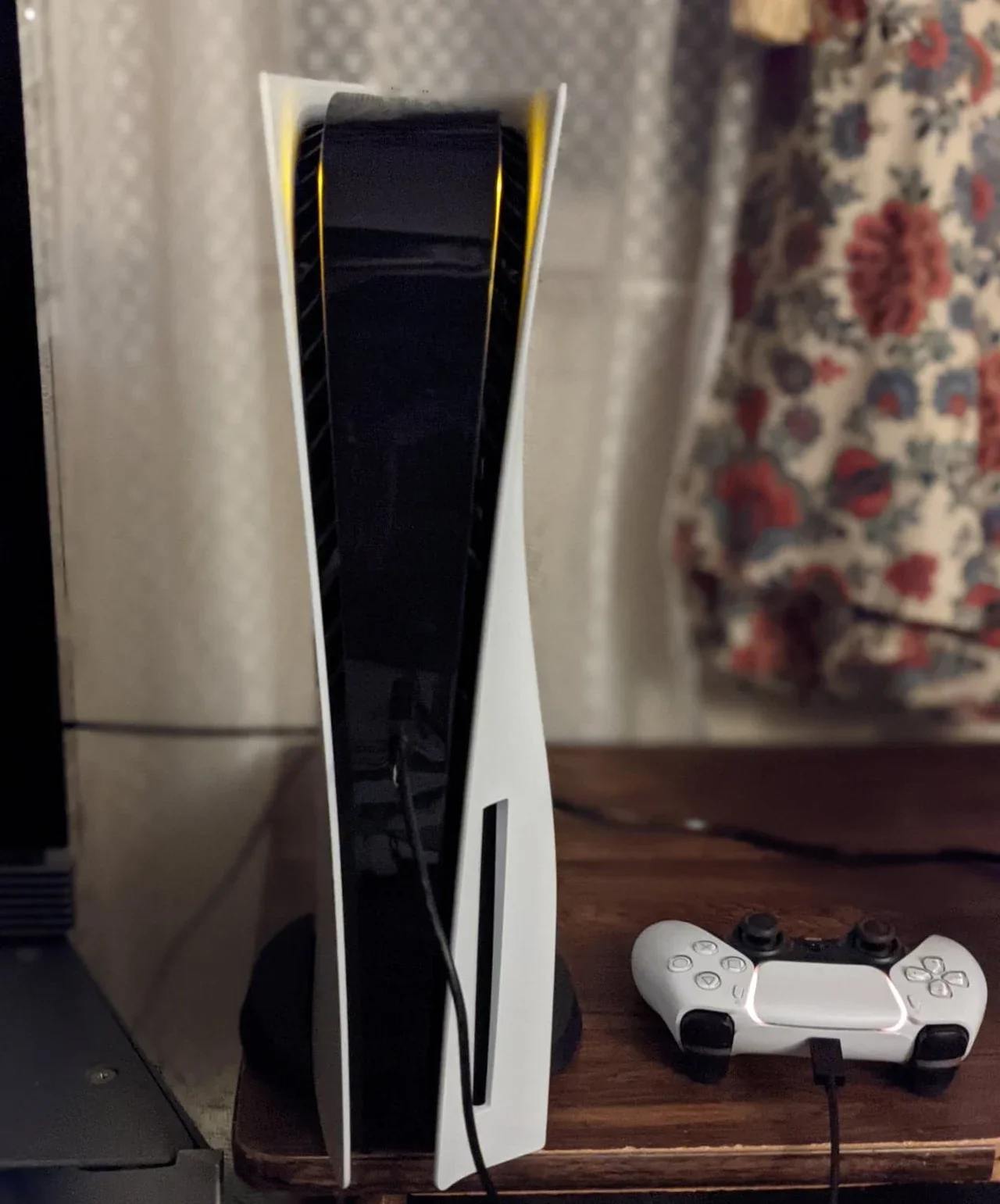 PlayStation 5 console standing upright with controller