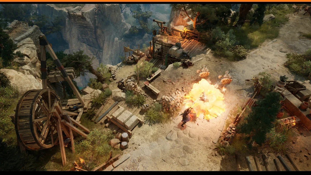 Top-down view of a hero casting a fiery explosion among enemies beside a wooden water wheel and scaffolding on a rocky hillside path
